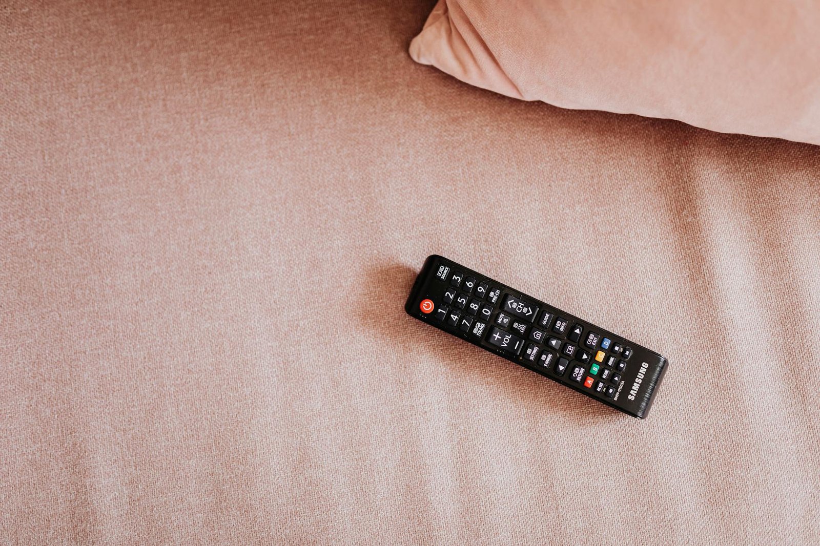 Free IPTV Player for Firestick — TV remote resting on a cozy fabric couch, ready to launch a streaming app | OTT-TV