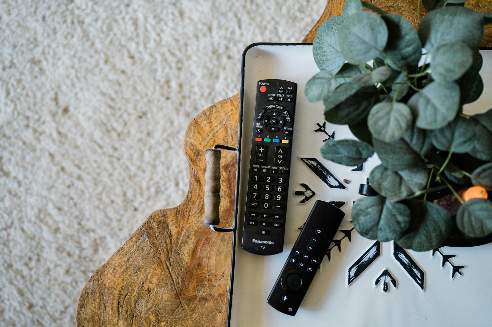 How to install TiviMate on Firestick — Top view of TV remote controls and a houseplant on a designer surface | OTT-TV