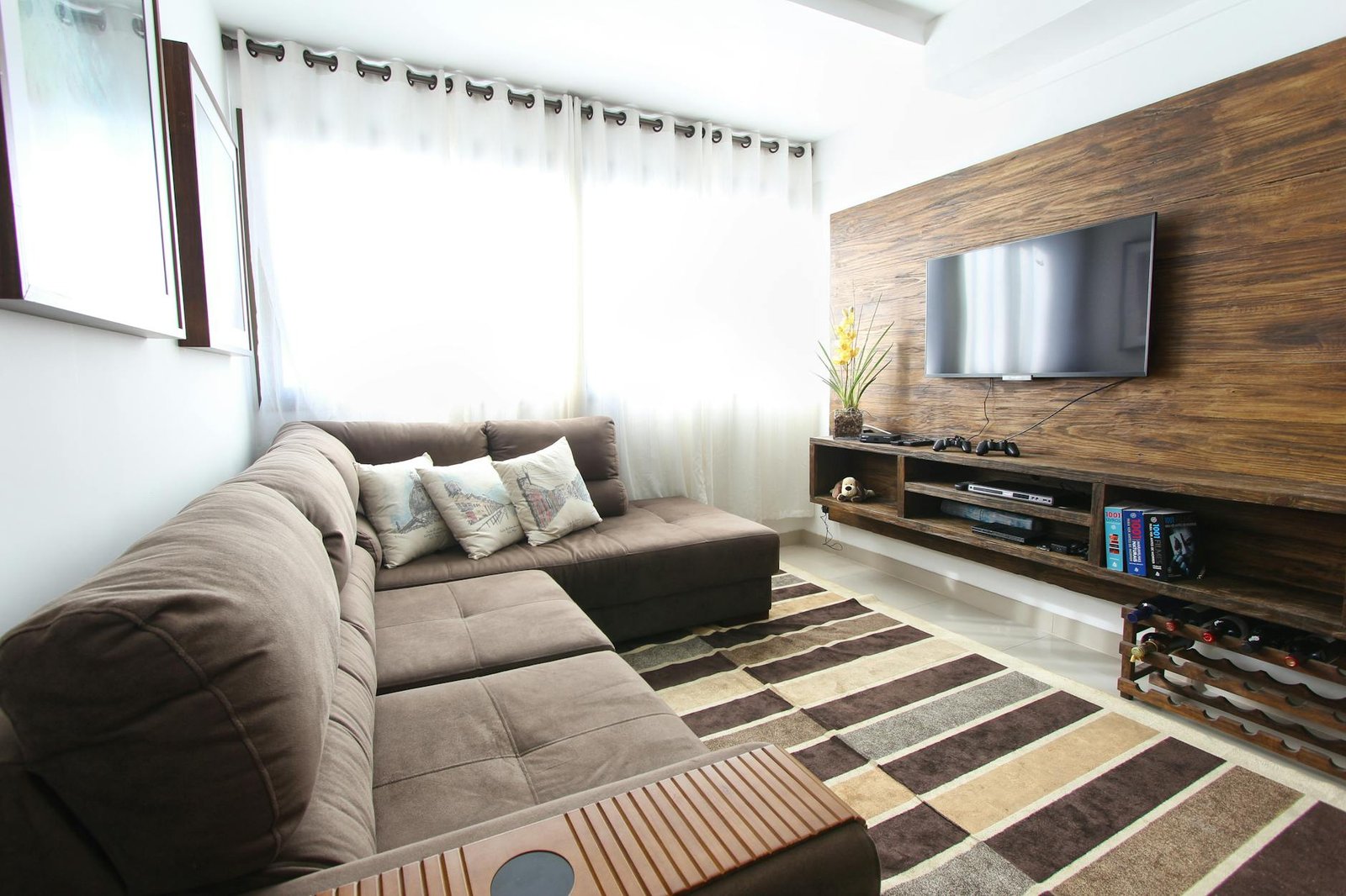 Modern living room with a wall-mounted Smart TV, leather sectional sofa and styled wood console — the streaming setup the top 5 IPTV providers in 2026 are built for