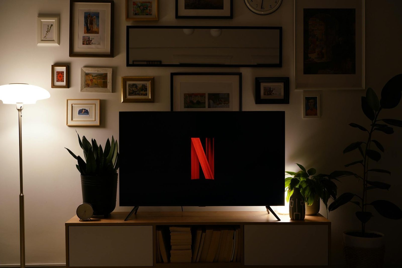 Large flat-screen Smart TV displaying the red Netflix logo on a wooden TV stand in an art-filled living room — that is what an IPTV subscription delivers, every channel and app on one screen